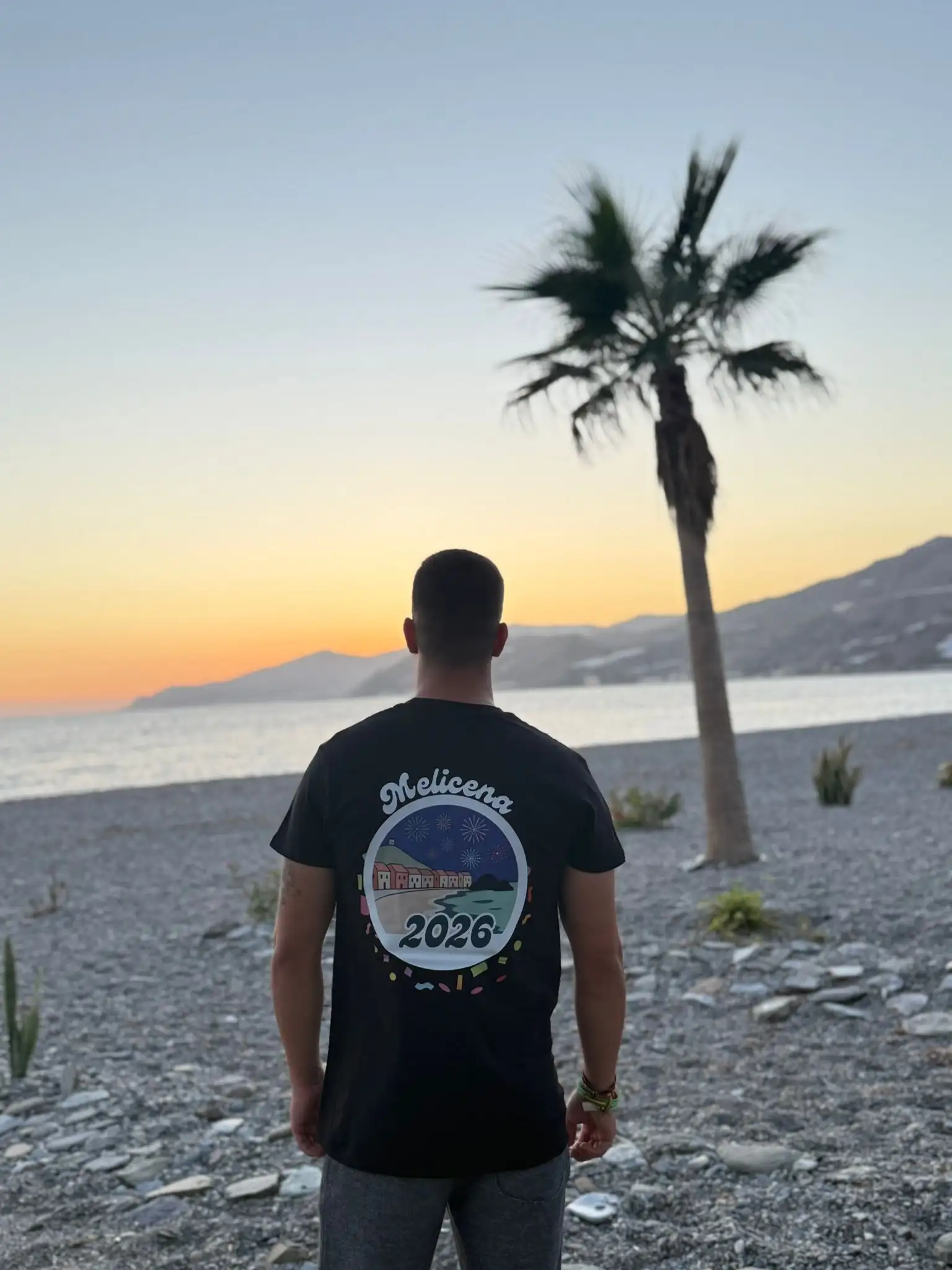 Juan con la camiseta negra de Melicena, trasera. La camiseta muestra una ilustración del pueblo por la noche.
